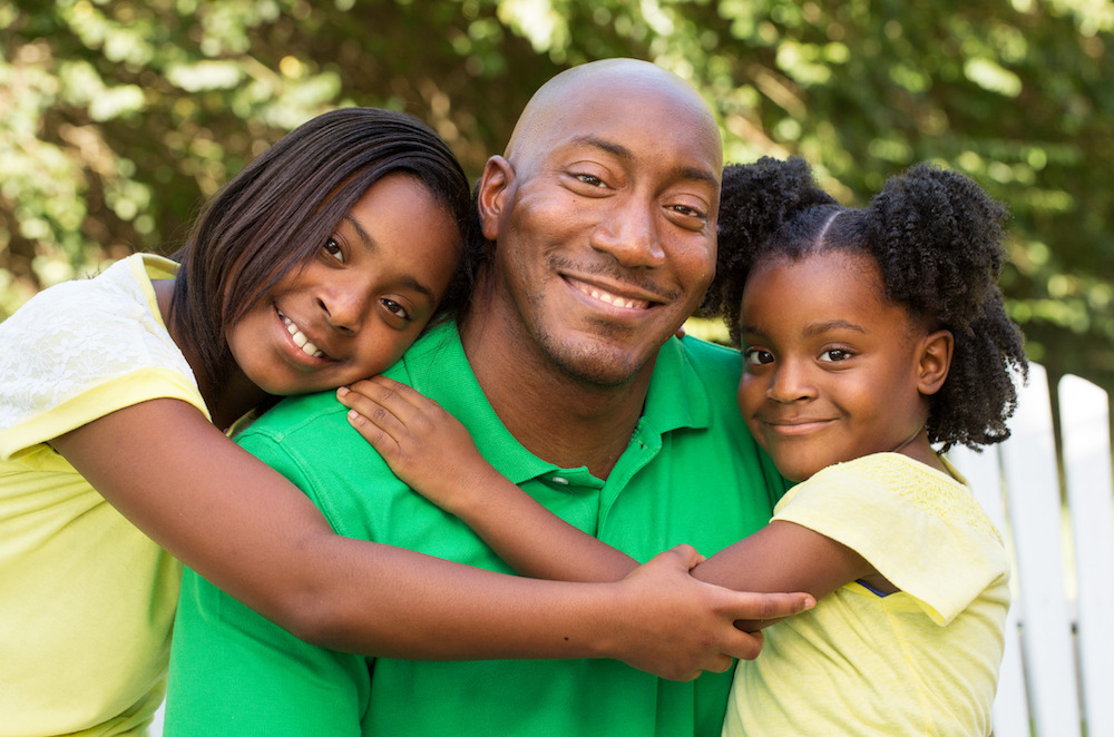 A father being embraced by his two daughters.