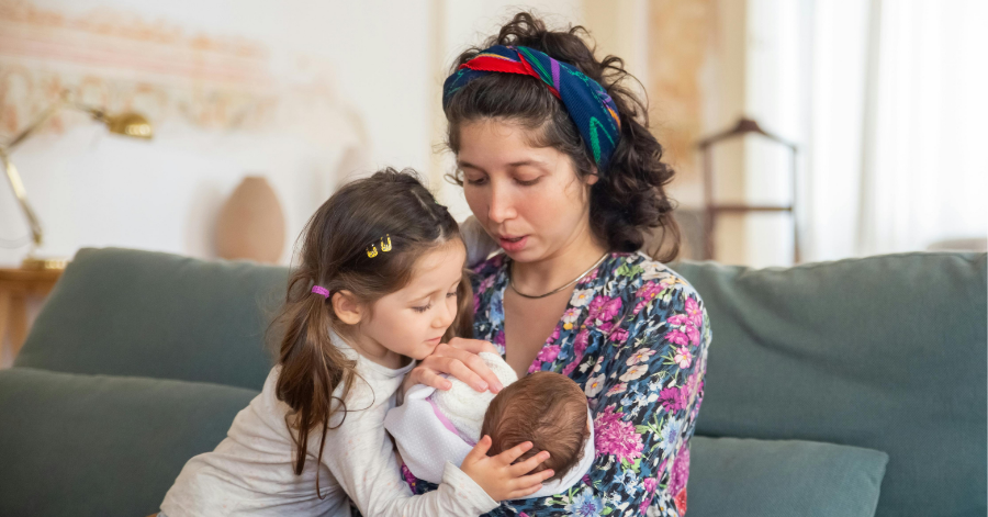 Mom holding baby with other young child