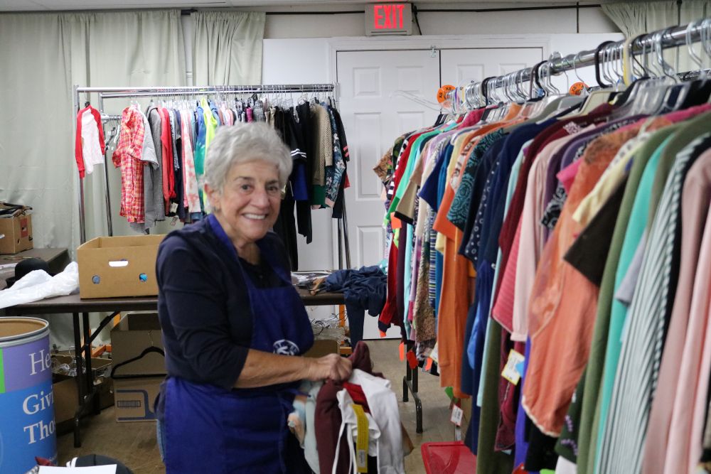 Lady holding clothes next to rack of clothes