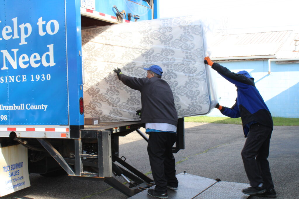 Men lifting mattress into SVDP truck