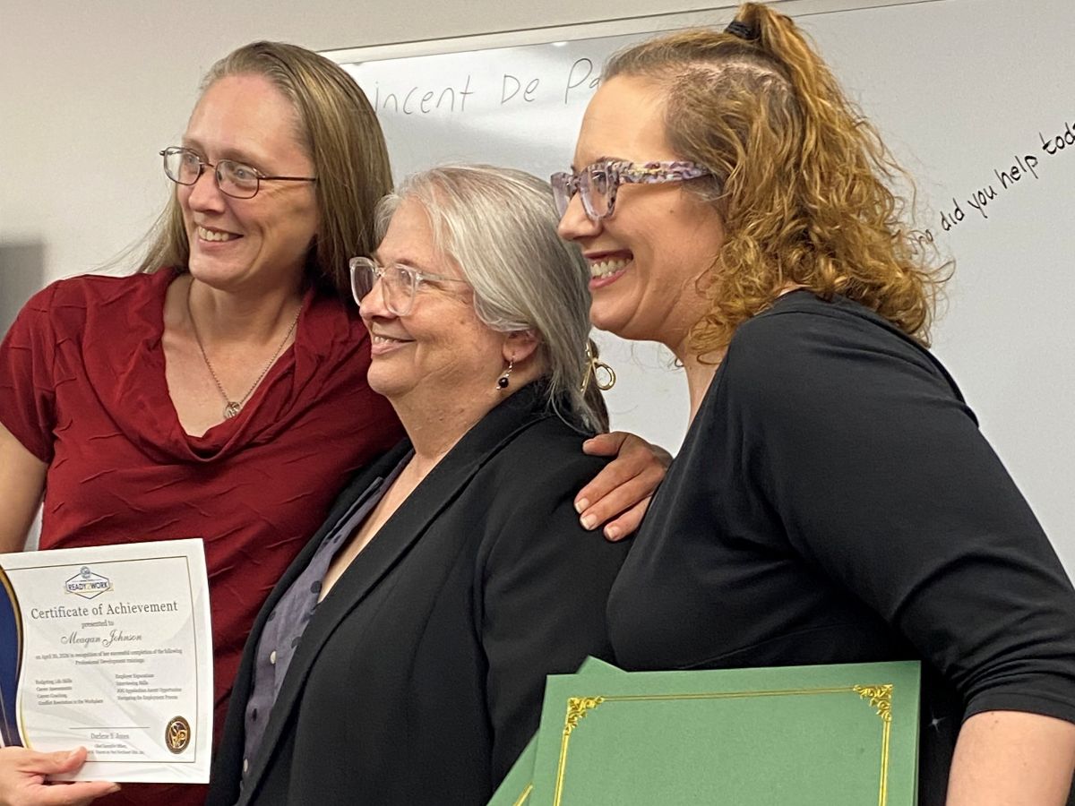 Women wearing glasses, smiling with arms around each other f