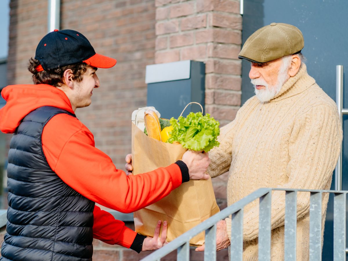 Young man handing older man a brown bag with food in it