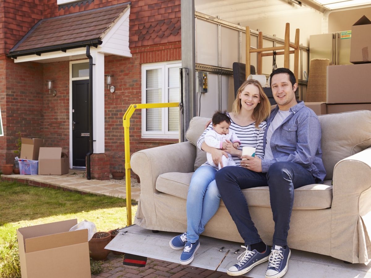 Family sitting on couch in front of new home